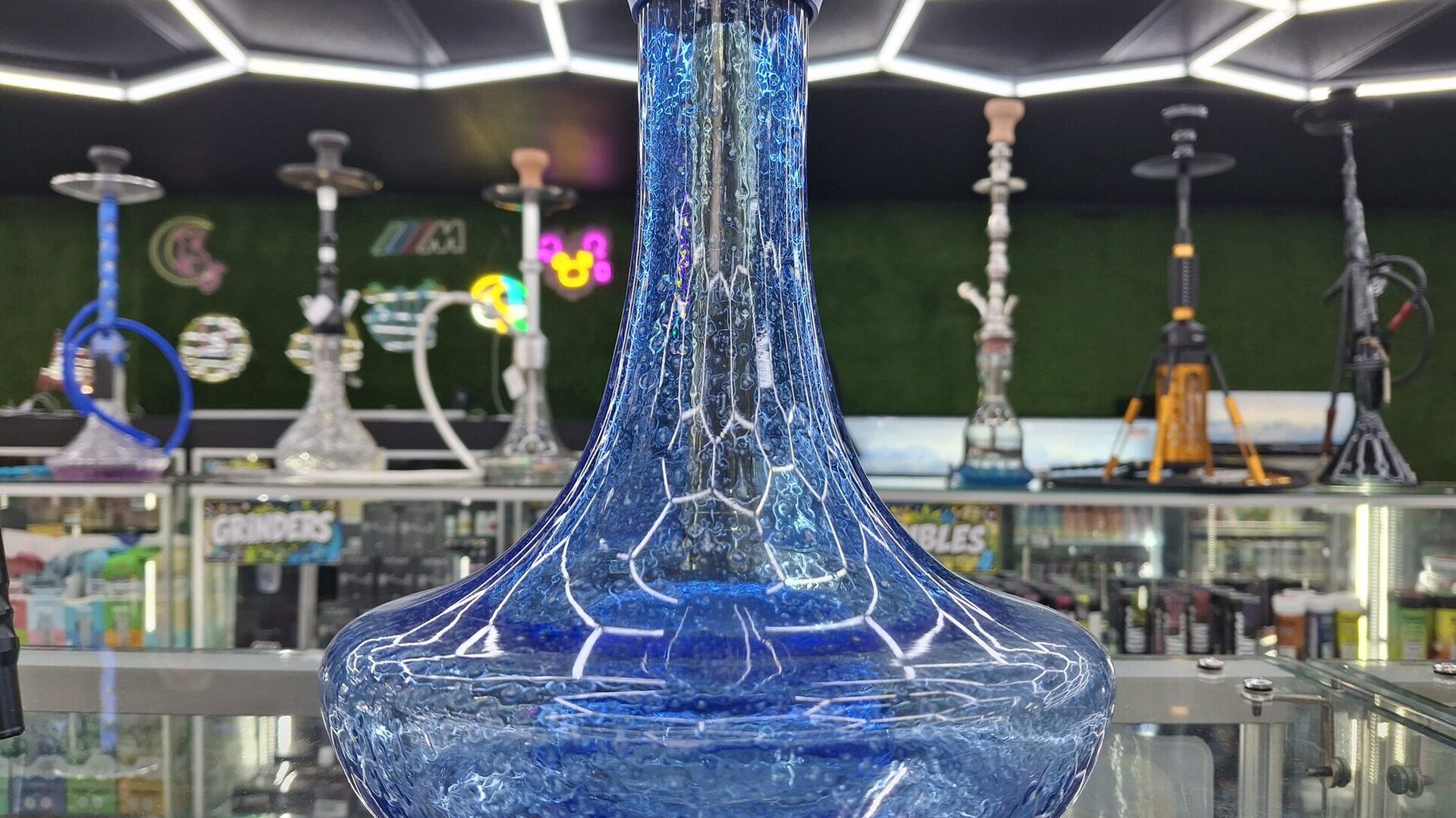 A blue glass hookah under the hexagonal LED ceiling in the Cloud Smoke Shop hookah room