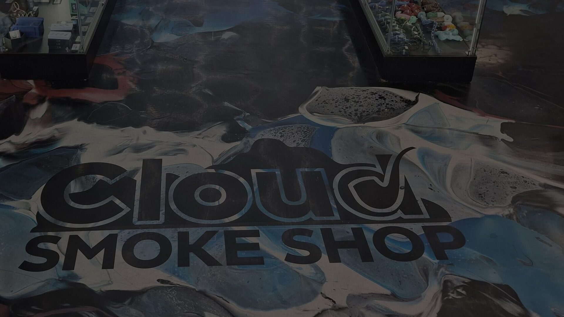 The Cloud Smoke Shop logo set into the poured blue, red, black and white epoxy floor between the display cases